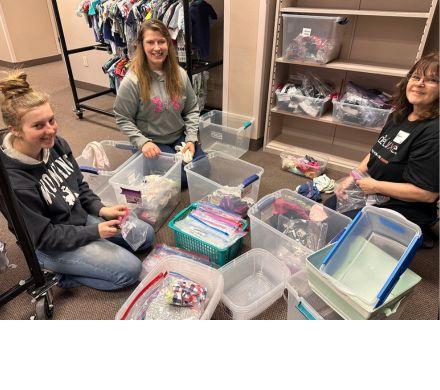 Three women sitting on the floor organizing socks